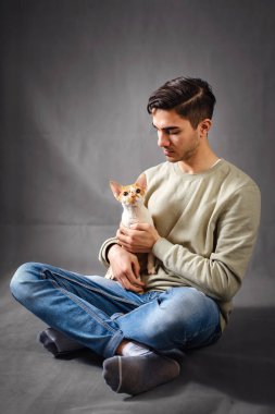 Ağızlığı tutan ve öpen adam sevimli Devon Rex kedisi