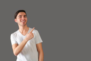 Gri arka planda duran bir adam parmağıyla işaret ediyor.