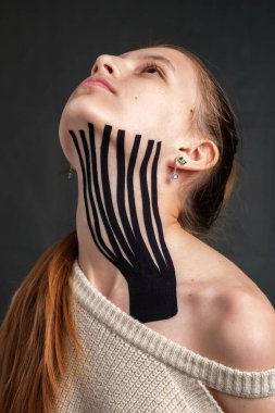 Kafkasyalı genç bir kızın boynuna yerleştirilmiş kineziyoloji bandı.