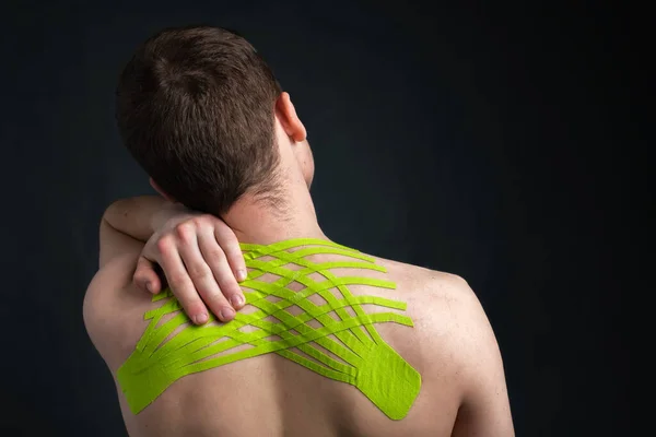 Hombre sosteniendo su cuello con cinesiología cinta médica aplicada para aliviar el dolor de espalda — Foto de Stock