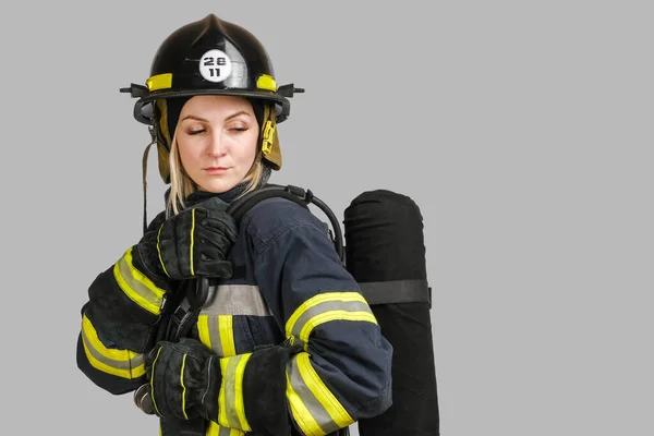 身穿消防队员制服的年轻高加索女人 背靠气罐 灰色背景 复制空间 — 图库照片