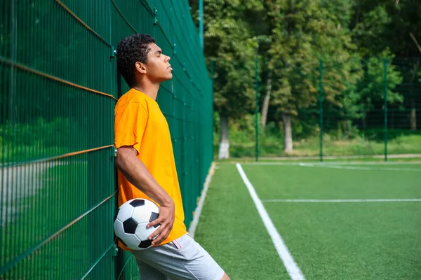 Spor Sahasında Çitlere Yaslanırken Futbol Topu Tutan Afro Amerikalı Bir — Stok fotoğraf
