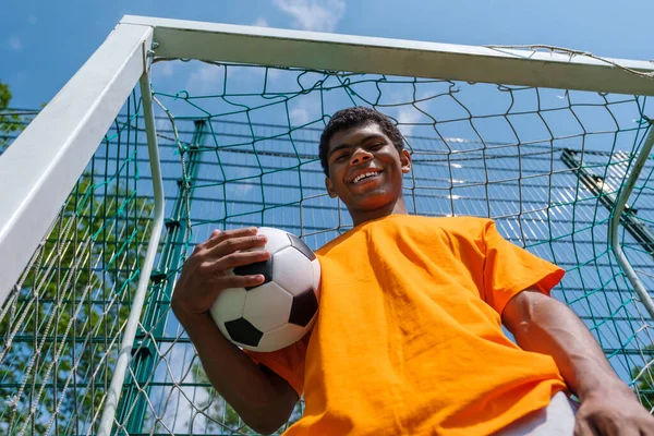 Mladý Usmívající Afroameričan Držící Fotbalový Míč Zatímco Stojí Fotbalovém Cíli — Stock fotografie