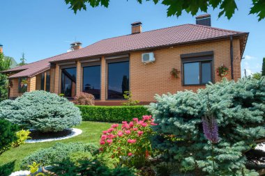 Evin önünde güzel budanmış çalıları olan Avrupa tarzı bir villa ve bahçe. Peyzaj tasarımı. Yüksek kalite fotoğraf