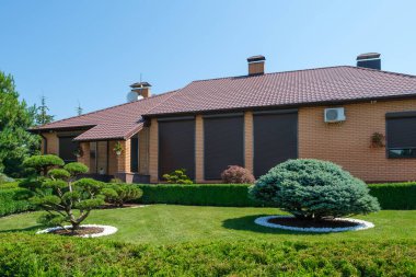 Avrupa tarzı villanın önündeki güzel budanmış bonsai, çalılar ve ağaçlarla güzel bir bahçe. Peyzaj tasarımı. Yüksek kalite fotoğraf