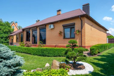 Avrupai villanın önünde güzel budanmış bonsai, çalılar ve taşlar olan bir bahçe. Peyzaj tasarımı. Yüksek kalite fotoğraf