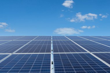 Mavi gökyüzünün altındaki bir güneş çiftliğinde sıra sıra güneş panelleri. Güneş enerjisi santrali, ekolojik alternatif bir elektrik kaynağı. Ön görünüm, boşluğu kopyala