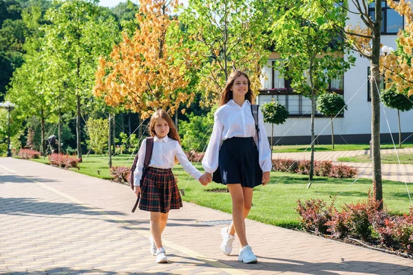 Δύο αδελφές κρατιούνται από το χέρι και πηγαίνουν μαζί σχολείο το πρωί. — Φωτογραφία Αρχείου