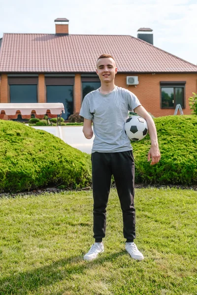 Uomo con braccio amputato tiene piede sul pallone da calcio mentre in piedi sul prato — Foto Stock