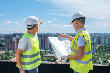 Beyaz kasklı adamlar bir inşaat planı hazırlayıp şantiyeyi teftiş edecekler.