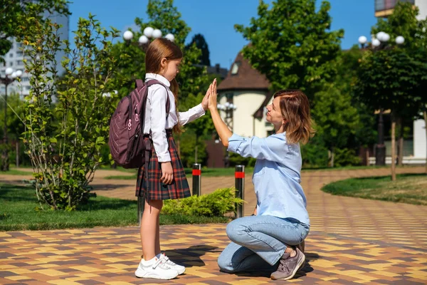 Καυκάσια μαθήτρια με σακίδιο και στολή λέει αντίο στη μητέρα της. — Φωτογραφία Αρχείου