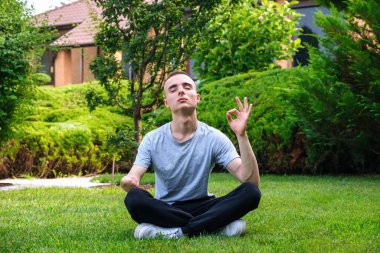 Özürlü genç adam dışarıda yoga yapıyor.