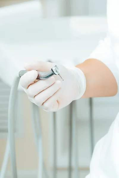 Der Zahnarzt hält in weißen Handschuhen ein Bohrwerkzeug in der Hand — Stockfoto