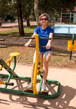 Açık hava fitness parkındaki formda kadın spor yapıyor.