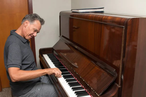 Mature Man at home entertaining himself playing the piano 