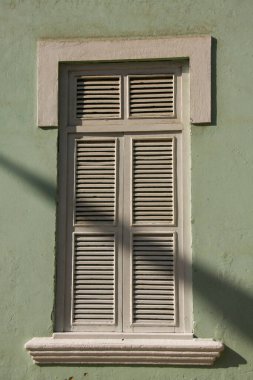 White Window against a green smooth textured wall 
