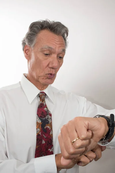 Older Mature Business Man wearing a white shirt and tie checking out the time on his wrist watch