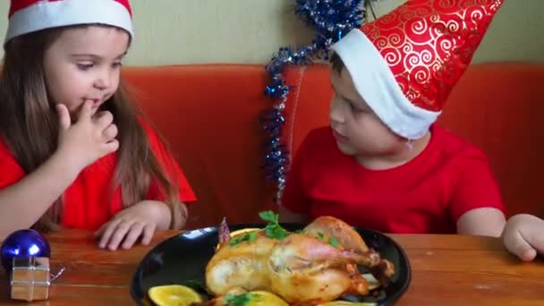 お母さんはお祝いの夕食のために鶏を切ります感謝祭の日、クリスマスまたは新年、子供たちはテーブルに座っています。ファミリーディナーオーブン焼きチキン七面鳥カレー — ストック動画