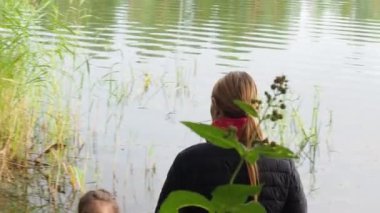 küçük kız annesine yakın göl ile arka görünümü oturma