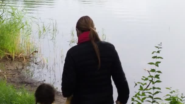 Liten flicka sitter med sin mamma nära sjön, Visa — Stockvideo