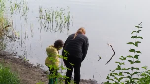 Petite fille assise avec sa mère près du lac, vue arrière — Video
