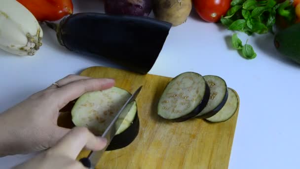Femela cu cuțit taie vinete la bord în bucătărie. Gătesc legume. pentru a face o tocană de legume sau o salată. vegetarianism, dietă, calorii scăzute, nutriție adecvată — Videoclip de stoc