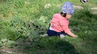 Gülümseyen sevimli, neşeli küçük kız yeşil çimlerin üzerinde duruyor. Küçük kız gölde yürümeyi öğreniyor. Güneşli bir gün ya da yaz günü