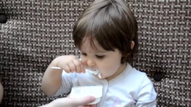 Happy infant baby boy spoon eats itself. baby girl toddler in a cafe feeds itself useful food. porridge, cottage cheese, yogurt spoon