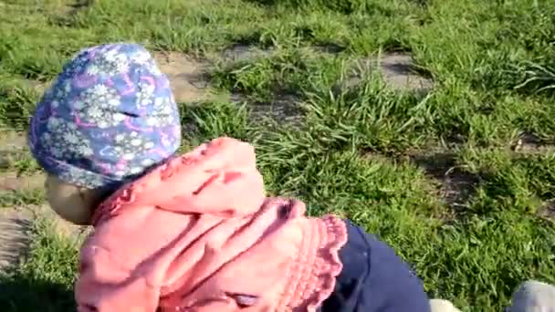 Sorrindo bonito brincalhão menina está de pé na grama verde. menina criança caminha ao redor do lago aprende a andar. sping ensolarado ou dia de verão — Vídeo de Stock