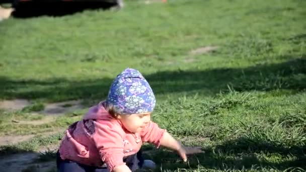 Sorridente carina giocoso bambina è in piedi su erba verde. ragazza bambino passeggiate intorno al lago impara a camminare. sole sping o giorno d'estate — Video Stock