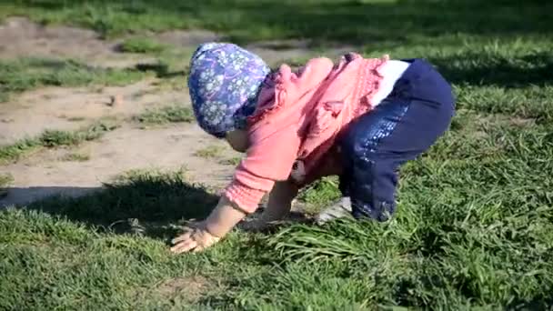 Uśmiechnięty cute zabawny dziewczynka stoi na zielonej trawie. dziewczynka maluch spacery wokół jeziora uczy się chodzić. słoneczny sping lub letni dzień — Wideo stockowe