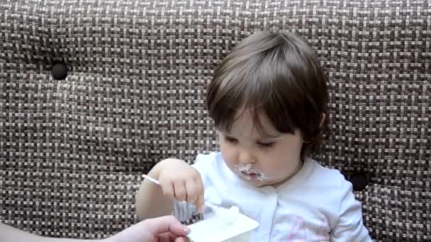 Happy infant baby boy spoon eats itself. baby girl toddler in a cafe feeds itself useful food. porridge, cottage cheese, yogurt spoon — Vídeos de Stock