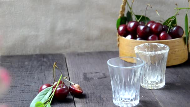 Bebida alcohólica vertiendo en dos tazas. casa hecha con licor de cereza y cereza sobre fondo de madera — Vídeos de Stock
