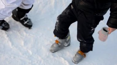 Kayak yapmaya hazırlanıyorum. Botları bağlıyorum. Anne oğlunun kayak botu giymesine yardım ediyor. Kış sporu. Açık hava.