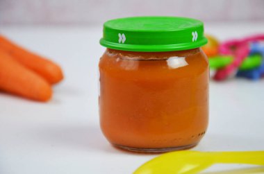 Bebek beyaz arka planda cam kavanozda kaşıkla ezilmiş.