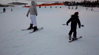 Yüksek dağlarda kayak yapan kayakçı gün ışığına karşı. Anne ve oğlu dağ kayağı yapmayı öğreniyor. Kış sporu. Açık hava