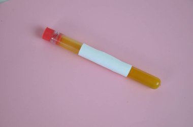 Pembe arka planda test tüplerinde sarı renkli sıvılar var.