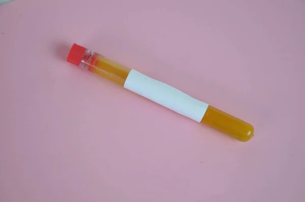 Líquidos coloridos amarelos em tubos de ensaio sobre fundo rosa — Fotografia de Stock