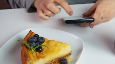 Bir kafede kremalı mascarpone peynirli yaban mersinli kek yiyen, telefonla mesaj yazan, haber izleyen, sosyal ağlar kuran bir kız. New York peynirli keki. Noel tatlısı. Sağlıklı yemek..