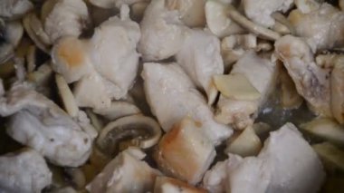Kız, masada tavuğun üstünde krema soslu mantarlı tavuk göğsü pişiriyor. en üstteki görünüm.