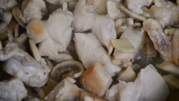 Fille cuisine poitrine de poulet avec des champignons en sauce à la crème sur une poêle sur la table. vue de dessus. — Video