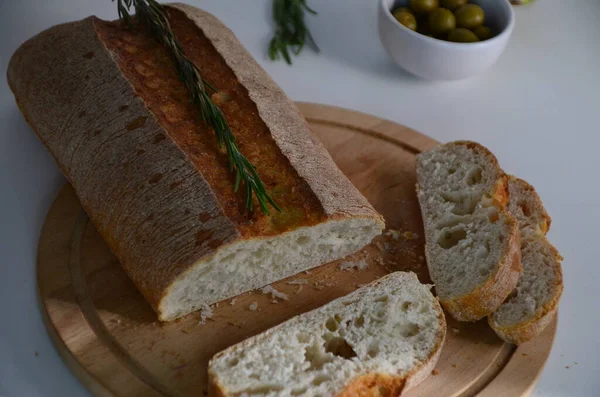 Geschnittenes Brot Ciabatta und Rosmarin auf Holz auf weißem Hintergrund — Stockfoto
