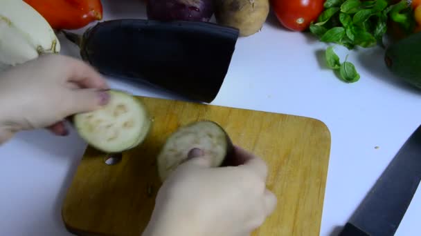 Mano femenina con cuchillo corta berenjena a bordo en cocina. Cocinar verduras. hacer un estofado de verduras o ensalada. vegetarianismo, dieta, bajas calorías, nutrición adecuada — Vídeos de Stock