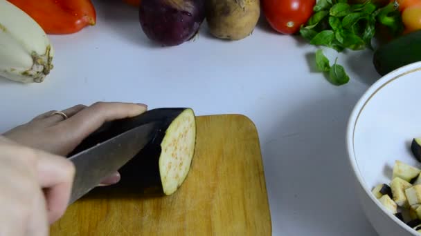 Žena ruka s nožem řeže lilky na palubě v kuchyni. Vařím zeleninu. udělat zeleninový guláš nebo salát. vegetariánství, strava, nízké kalorie, správná výživa — Stock video