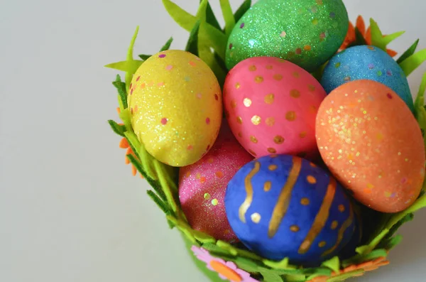 Grattis på påskdagen. Påskägg koncept. Närbild Färgglada påskägg i bo och korg grön crass på vit trä bakgrund. — Stockfoto