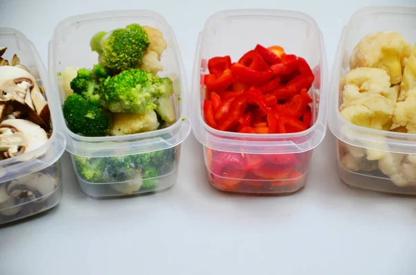 Δίσκοι με ωμά λαχανικά για κατάψυξη. Αποθηκεύοντας για χειμερινή αποθήκευση σε πλαστικά δοχεία, βάζει σε ένα κουτί για να παγώσει κόκκινες πιπεριές, μπρόκολο, κουνουπίδι, καρότα — Φωτογραφία Αρχείου