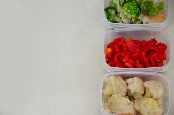 冷凍用の生野菜とトレイ。プラスチック容器に冬の貯蔵のために備蓄し、赤ピーマン、ブロッコリー、カリフラワー、ニンジンを凍らせるために箱に入れます。 — ストック写真