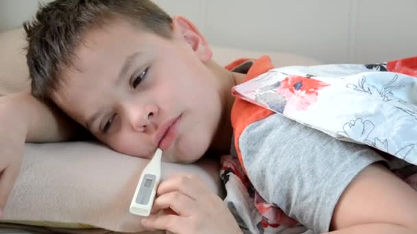 Băiatul se află acasă cu febră, cu tuse, este tratat. Copil bolnav întins în pat, odihnindu-se acasă — Videoclip de stoc