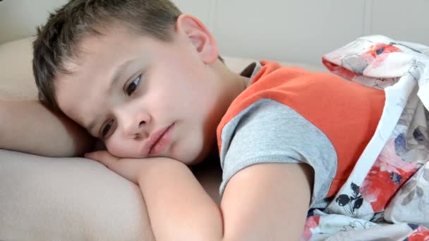 少年は熱で家に横たわって咳をして治療されています。病気の子供の男の子がベッドに横たわって、家のお母さんで休んでスプーンにポーションを注ぐ — ストック動画