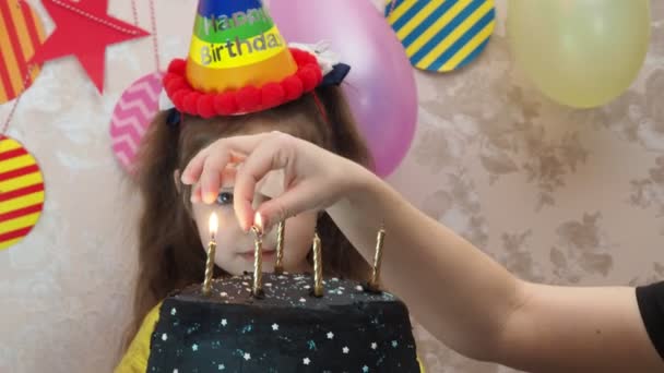 誕生日ケーキのかわいい女の子の肖像画。キャップの女の子は彼女の誕生日を祝う、楽しい、パイプを吹く、ケーキにろうそくを吹き消す、ケーキを食べる、ジュースを飲む、マスクを着用する — ストック動画